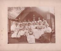 Untitled sepiatone photograph, showing 14 young women and three elders in Victorian-era "Sunday best" clothing, at cabin door