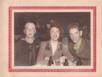 Original tinted photograph of a WWII sailor and a soldier, flanking a woman in "jitterbug" garb of the day, all seated at a table
